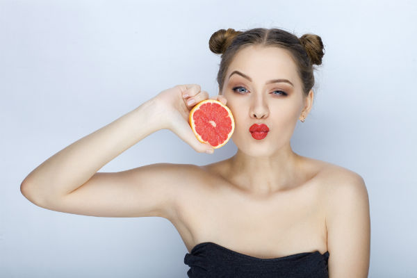 בחורה צעירה מחזיקה תפוז אדום