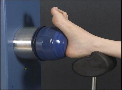 כף רגל נחה על משענת שחורה ומוצמדת לרכיב עגול של מכשיר הארטרוסקופ שמיועד לטיפול בגלי הלם
